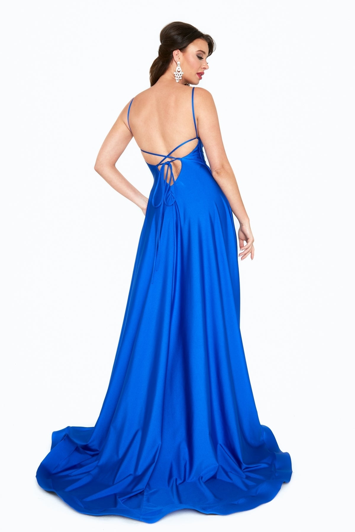 A woman stands against a white background, facing away from the camera, wearing the Long A-Line Prom Dress with Pockets: Atria 6521H in bright blue, featuring thin straps and a low open back.